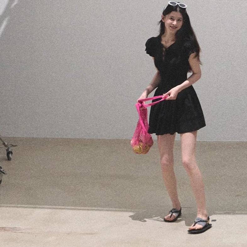 Black fitted flutter sleeve mini dress styled with slide sandals and a pink mesh tote bag
