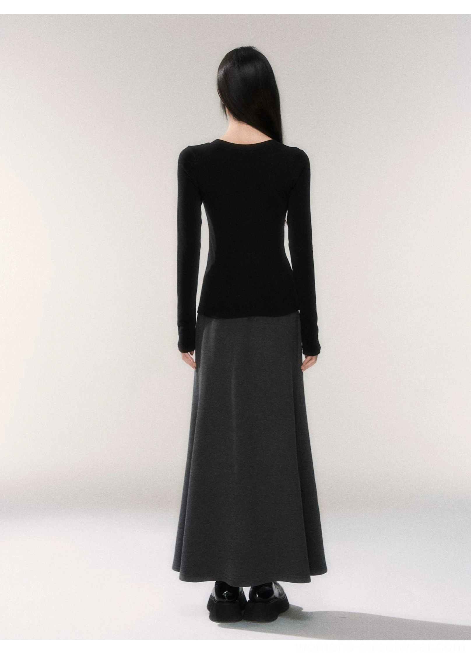 Back view of a fitted black long sleeve henley knit top showing its streamlined silhouette and elongated sleeves