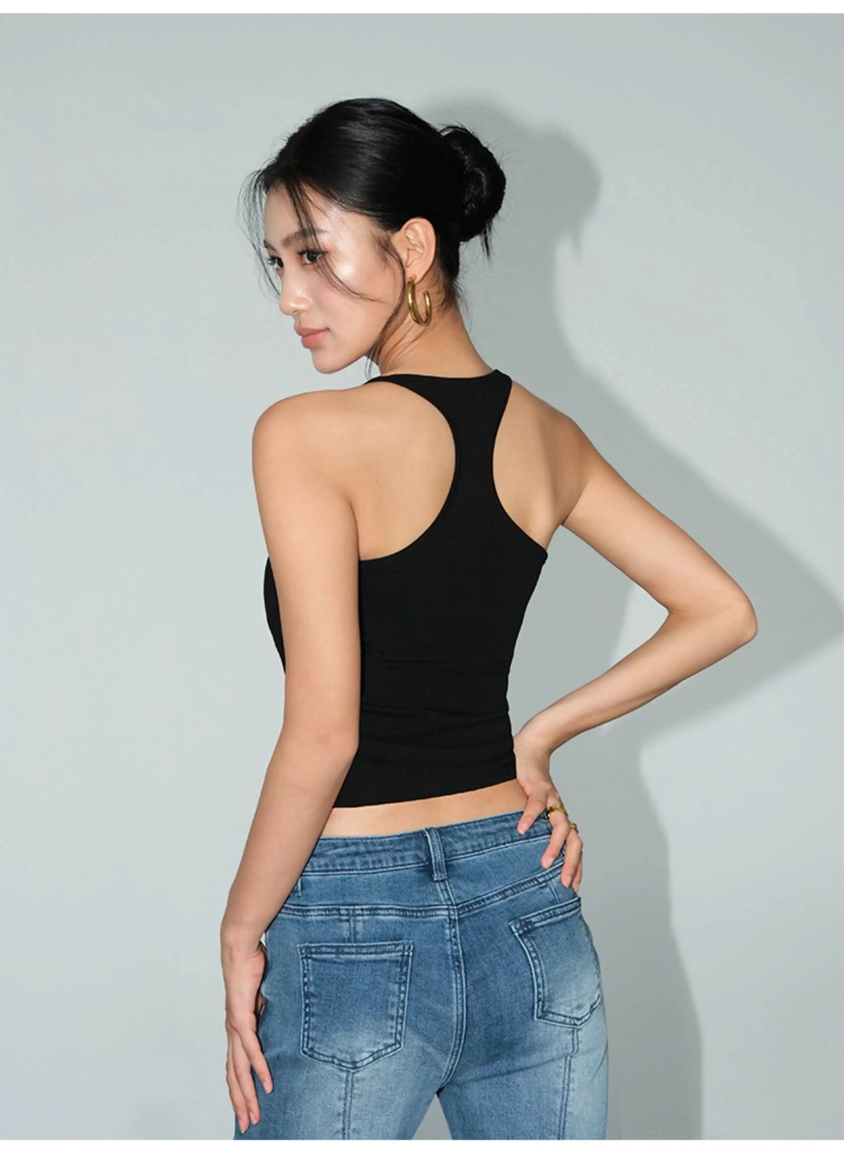 Black racerback fitted knit crop tank shown from a three-quarter back angle with denim jeans