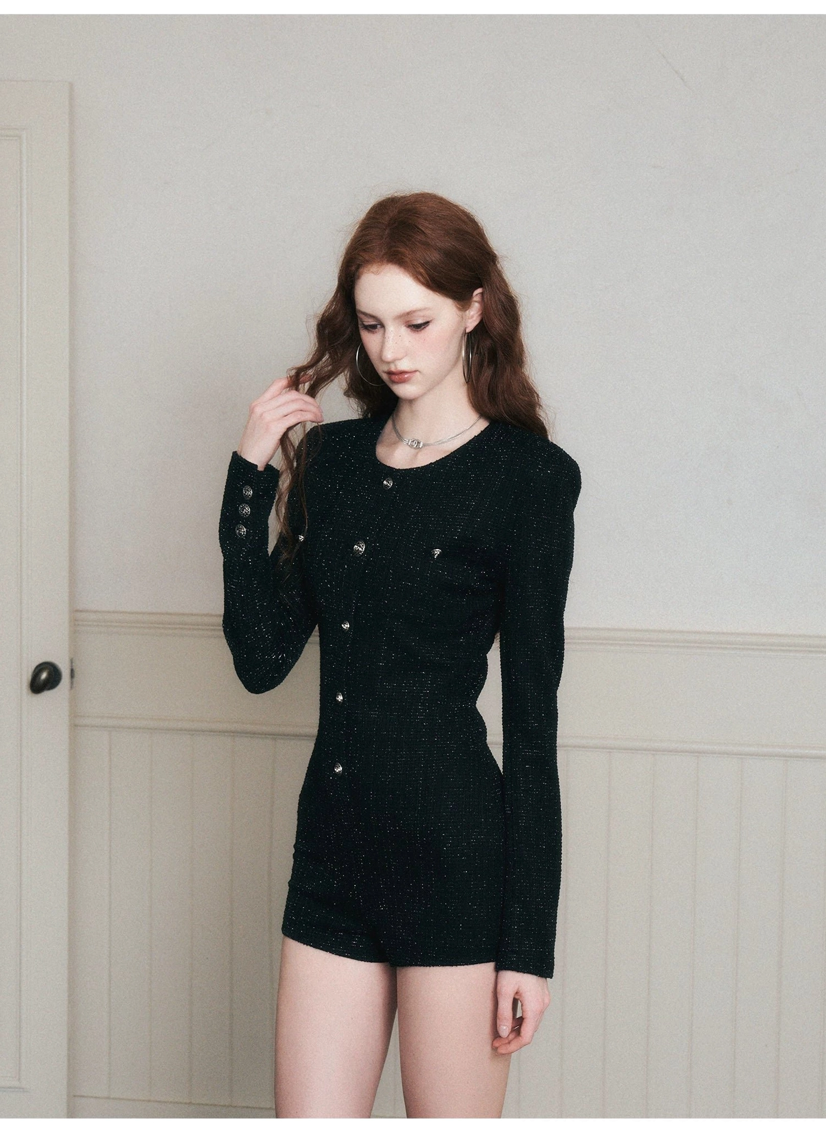 Front three-quarter casual view of a woman wearing a black fitted tweed romper with long sleeves, button front styling, and a modern Korean streetwear feel