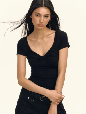 Close-up of black fitted twist front cropped streetwear top with ruched bust detail, deep scoop neckline, short sleeves, and exposed waist