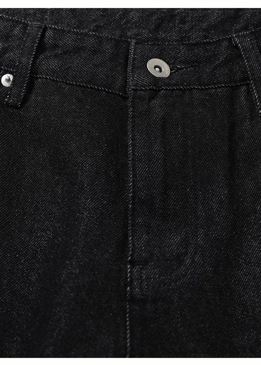Close-up of black flare jeans front waistband with metal button belt loops rivets and dark twill texture