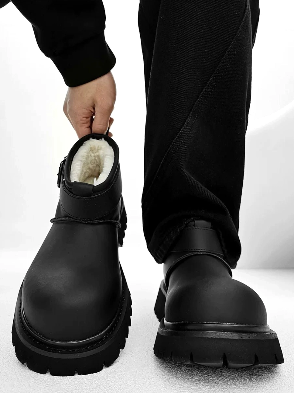 Black fleece-lined buckle platform ankle boots with silver strap and chunky lug sole shown on foot and in a studio product view