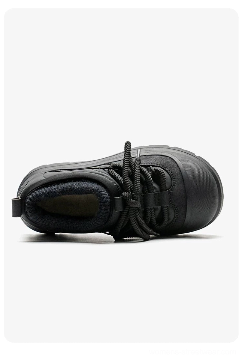 Side bottom view of a black fleece-lined platform sneaker showing exposed fuzzy lining, lace-up detail, and deep lug outsole