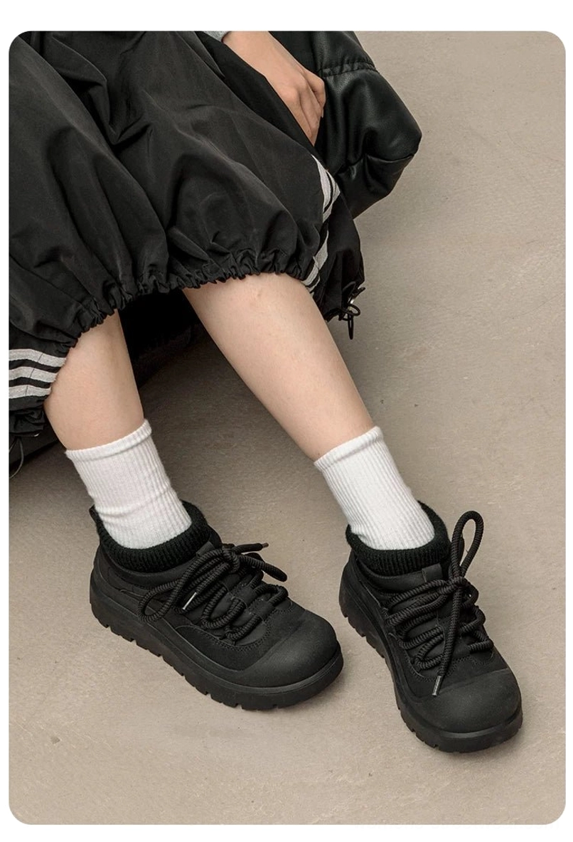 Medium lifestyle view of black fleece-lined platform sneakers worn with a puffer midi skirt and white socks