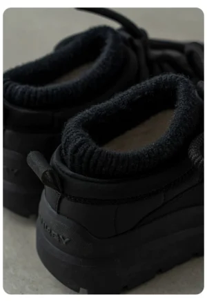 Close-up rear side view of black fleece-lined platform sneakers showing ribbed collar, heel pull tab, and elevated streetwear sole