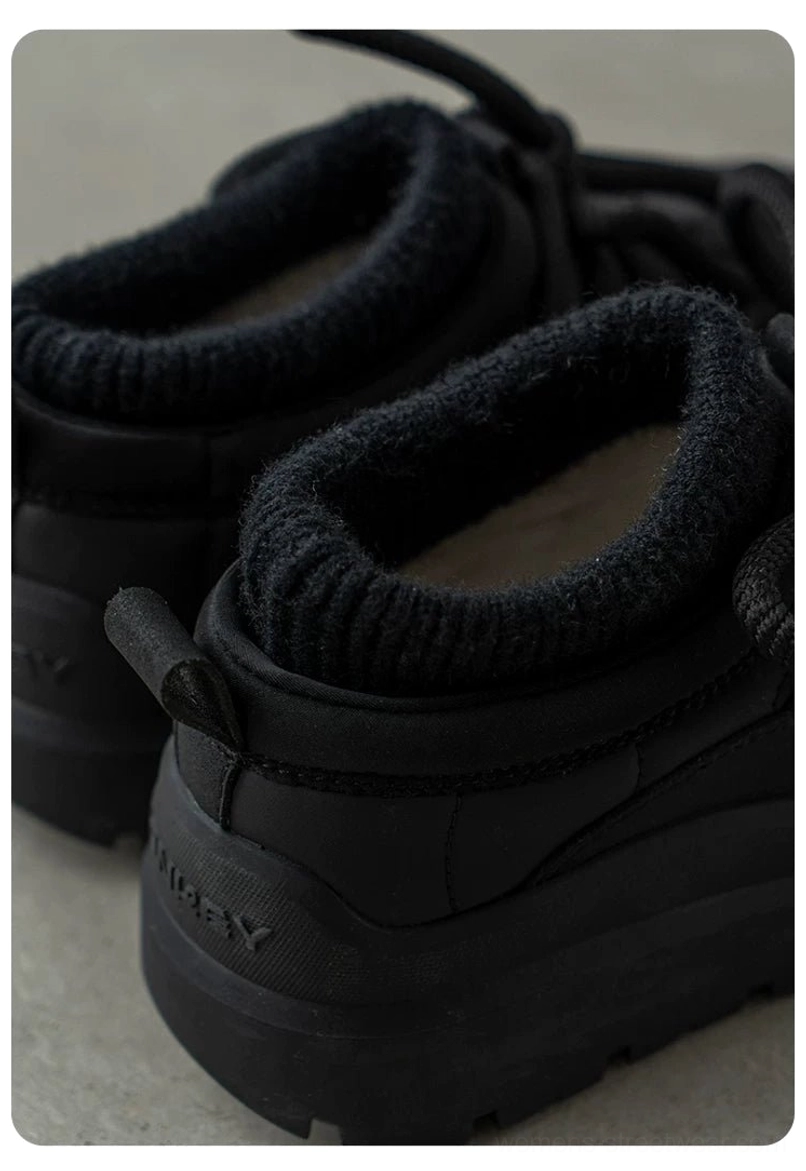 Close-up rear side view of black fleece-lined platform sneakers showing ribbed collar, heel pull tab, and elevated streetwear sole