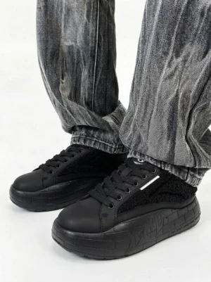 Black fleece platform sneakers styled with gray tie-dye jeans in a casual Y2K streetwear outfit