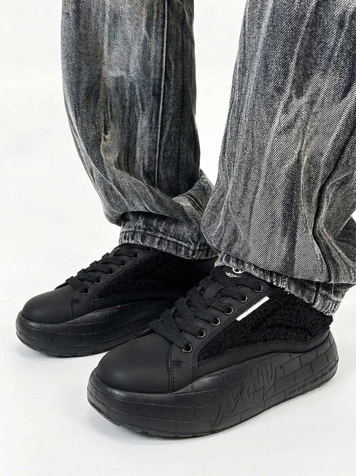 Black fleece platform sneakers styled with gray tie-dye jeans in a casual Y2K streetwear outfit