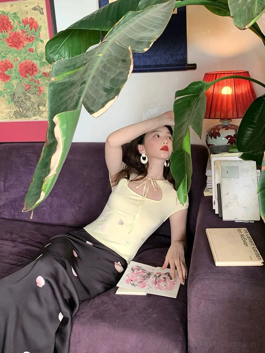 Side view of a woman wearing a relaxed black floral maxi skirt with soft drape and delicate pink flower print