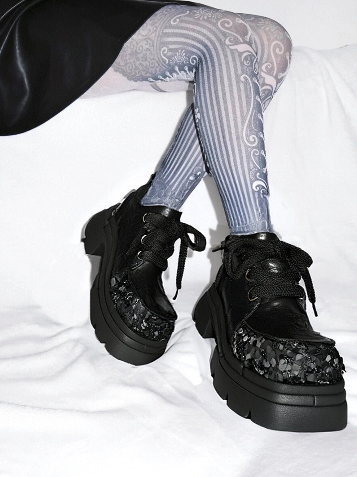 Black floral sequin platform derby shoes paired with silver gray patterned tights, showing embellished toe caps and chunky platform soles