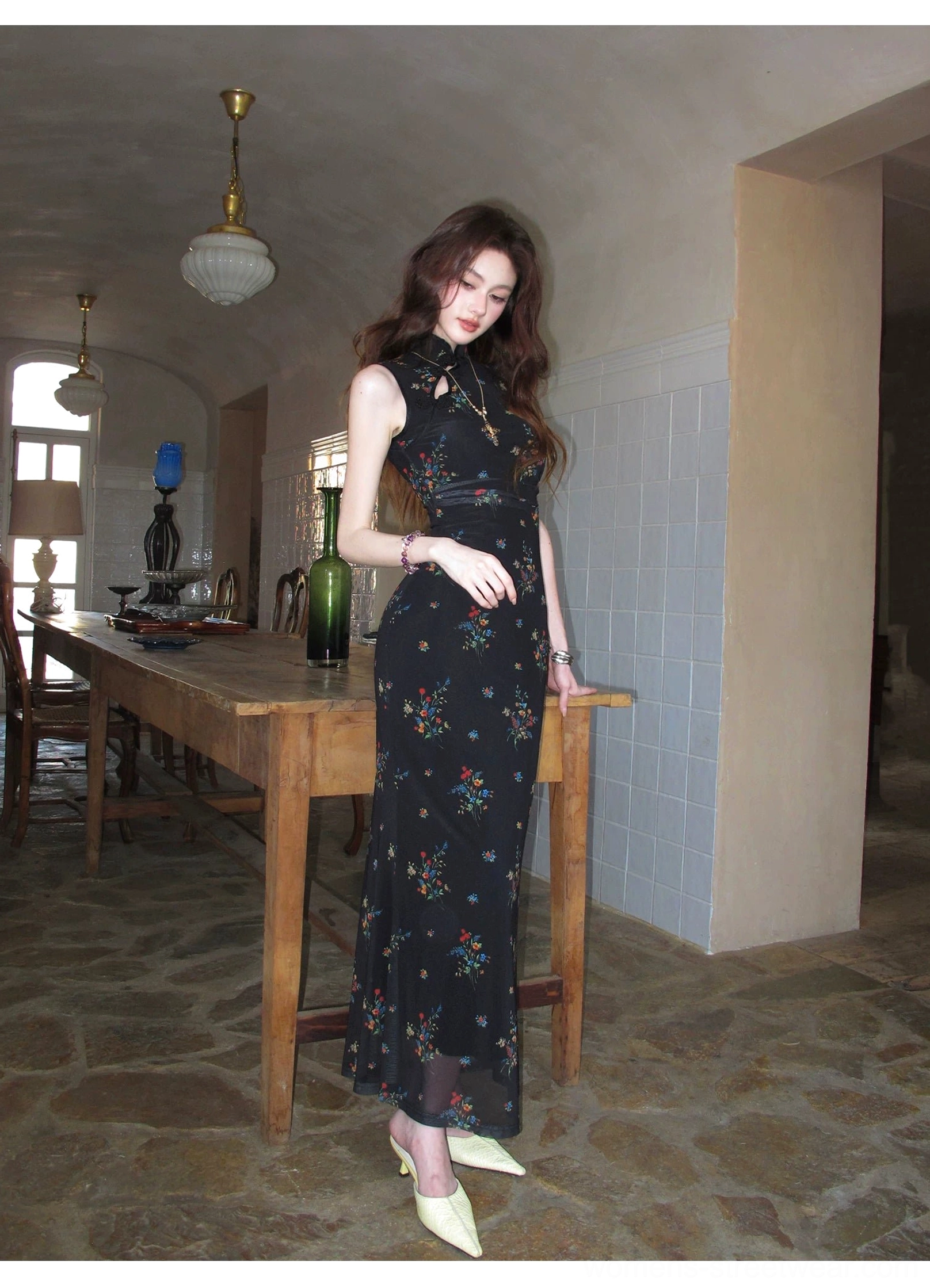 Full body side view of a black floral sleeveless cheongsam dress with fitted bodycon silhouette, delicate floral print, and long streamlined skirt