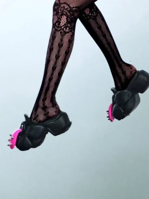 Low angle view of black flower platform slip-on shoes styled with patterned fishnet stockings in an edgy streetwear outfit