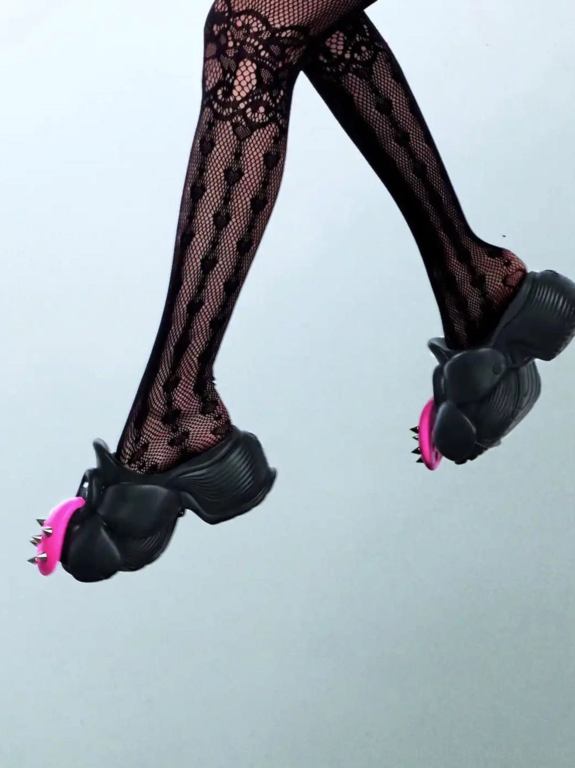 Low angle view of black flower platform slip-on shoes styled with patterned fishnet stockings in an edgy streetwear outfit
