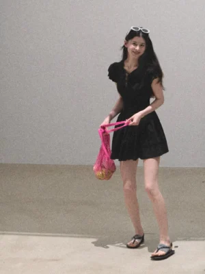 Black flutter sleeve mini dress styled with a pink mesh tote bag in a minimalist studio setting