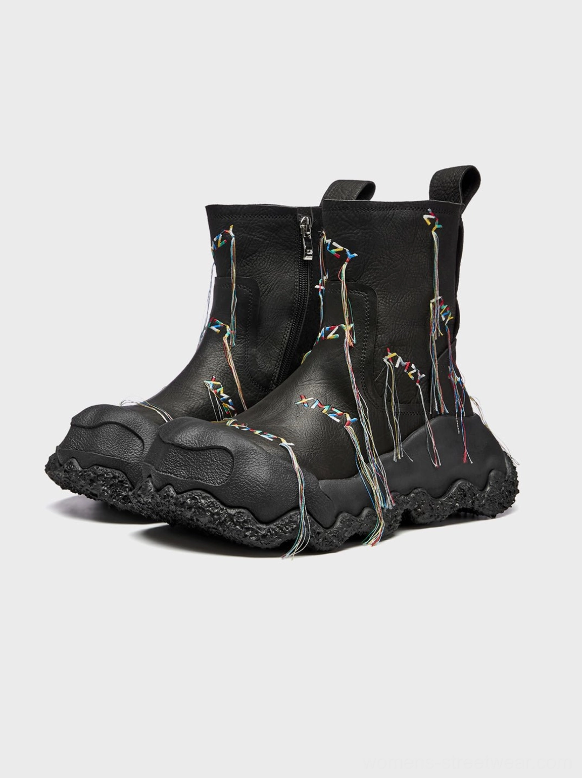 Front three-quarter view of pair of black fringe western ankle boots featuring colorful tassel details and chunky textured soles