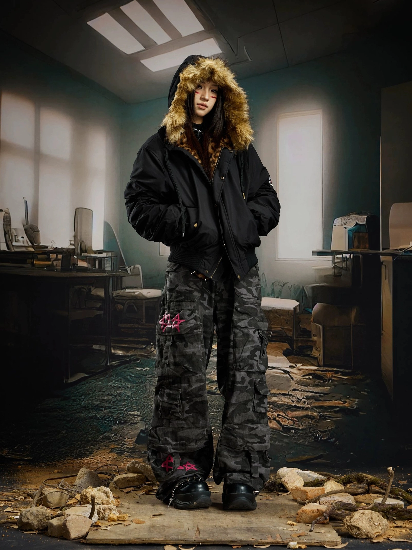 Female model wearing a relaxed black fur trim hooded bomber jacket with the hood up and camo cargo pants