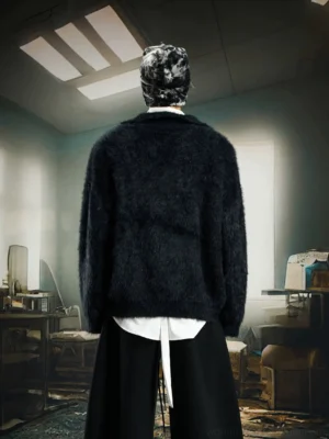 Black oversized fuzzy knit sweater shown from the back on a male model wearing a printed bucket hat with layered streetwear styling