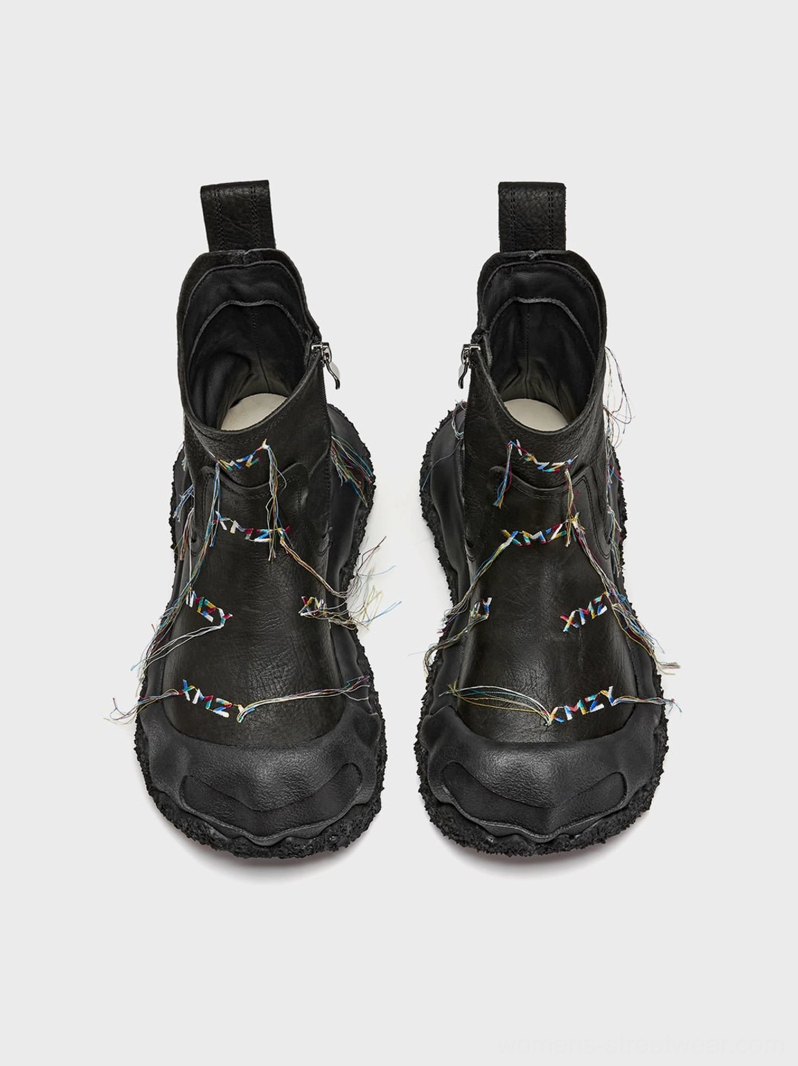 Top view of black geometric fringe western ankle boots showing boot openings, side zipper, colorful tassel trims, and chunky sole