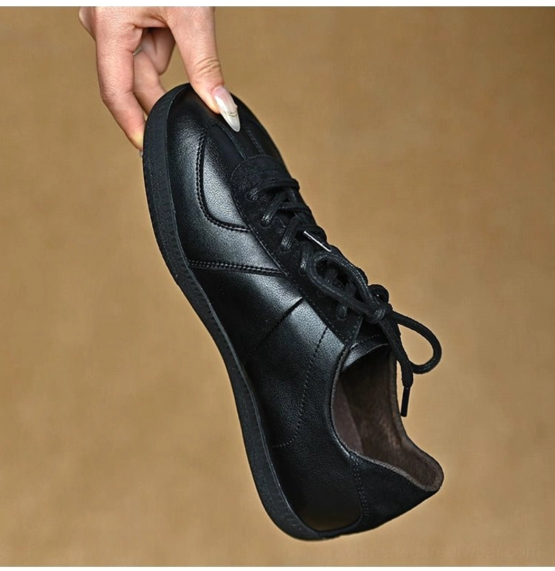 Three-quarter view of a black German trainer-inspired leather sneaker with suede-style toe cap and lace panel accents