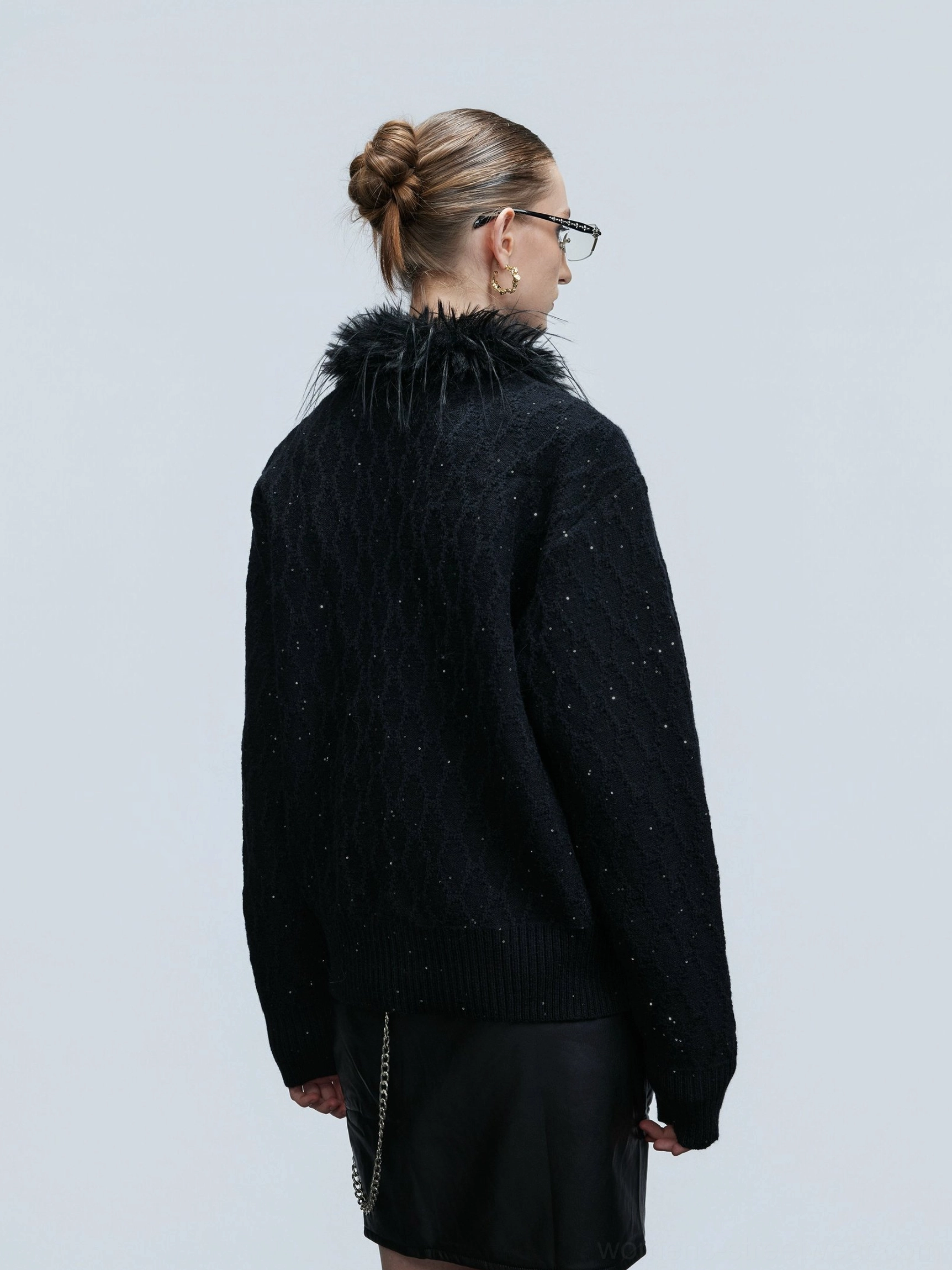 Back view of black cropped glitter cable knit cardigan with textured twisted knit pattern and faux feather collar