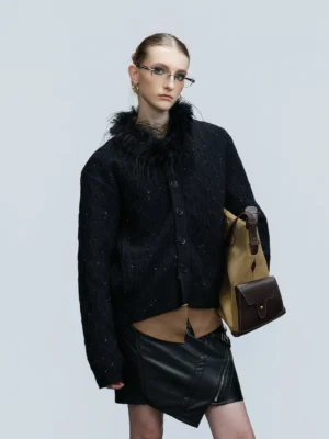 Black glitter cable knit cardigan with detachable faux feather collar worn with leather mini skirt in studio front view