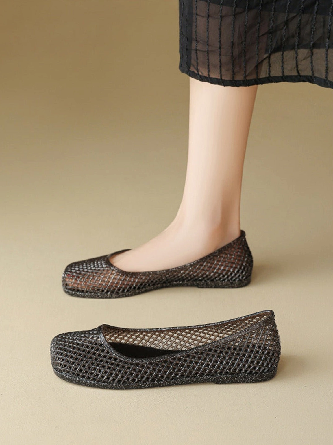 Black glitter mesh jelly ballet flat worn with a sheer black skirt and bare ankle