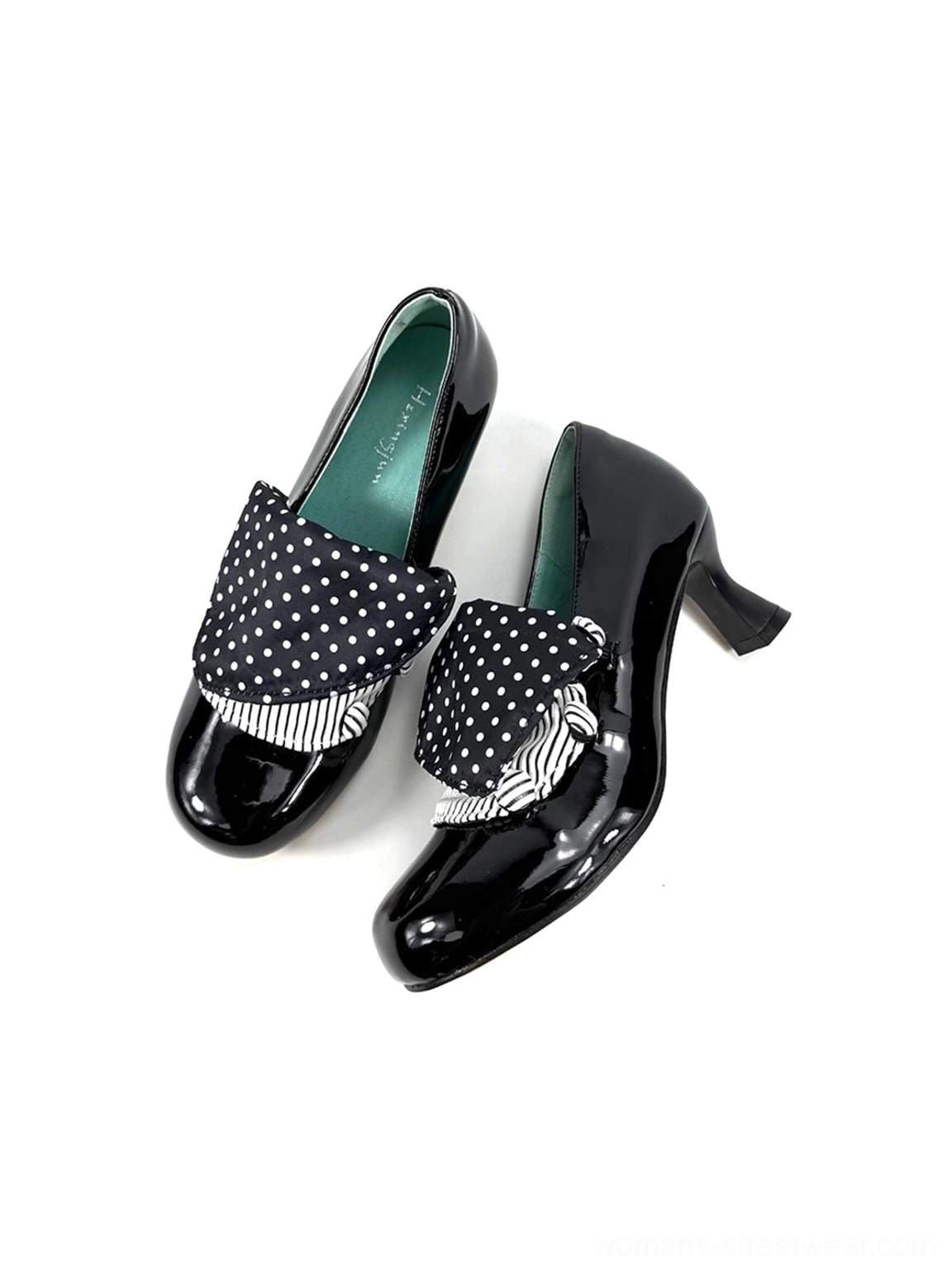 Three-quarter side view of black glossy patent pumps with compact polka dot bow accents and dark green lining