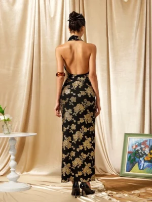 Back view of a black and gold cheongsam inspired maxi dress showing the open back halter neckline and gold floral print