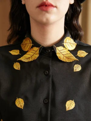 Close-up of black golden leaf embroidered oversized streetwear shirt with pointed collar and front button placket
