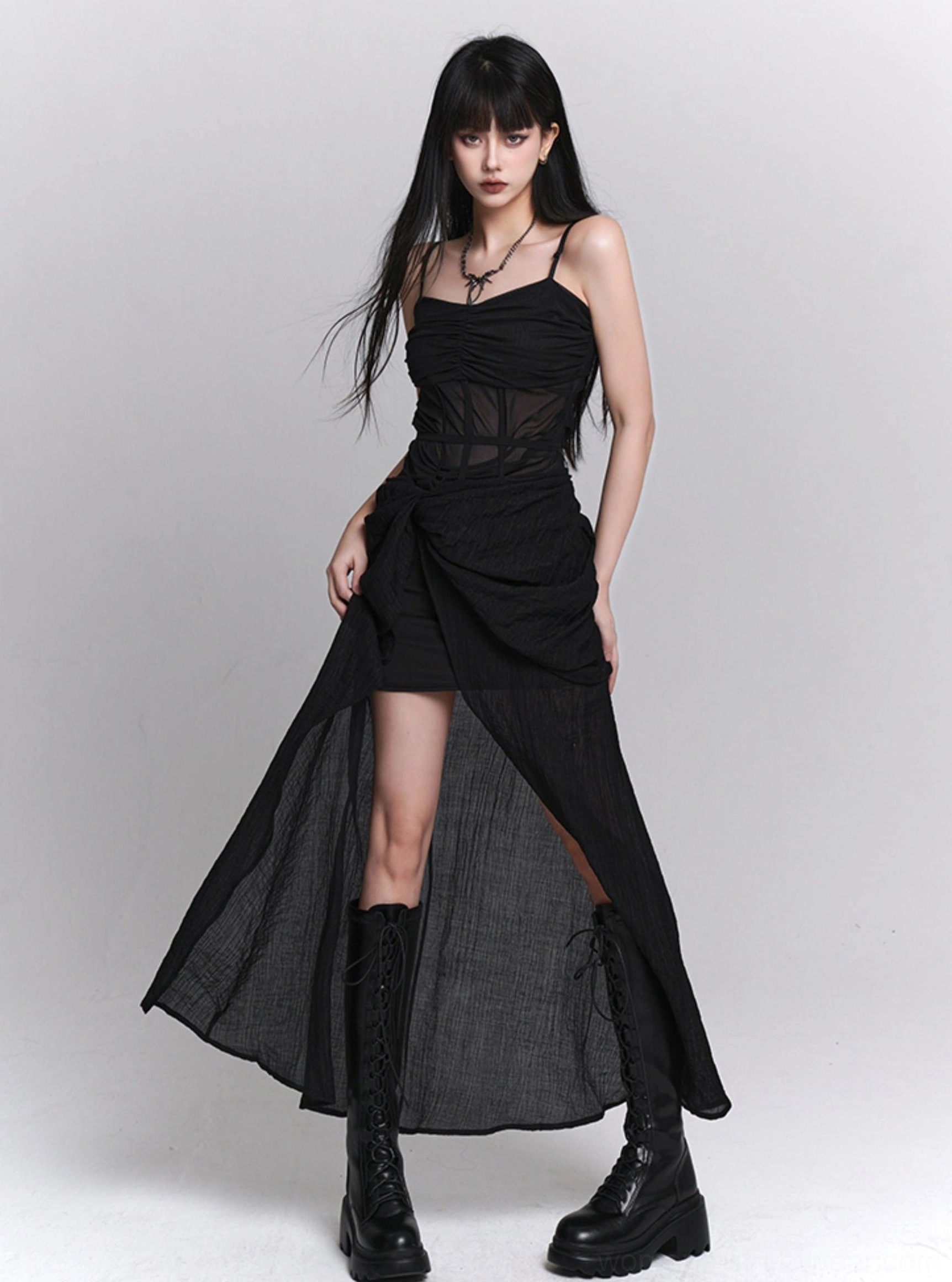 Side view of black gothic asymmetrical slip dress with sheer bodice, twisted front draping, long sheer overlay, and side slit