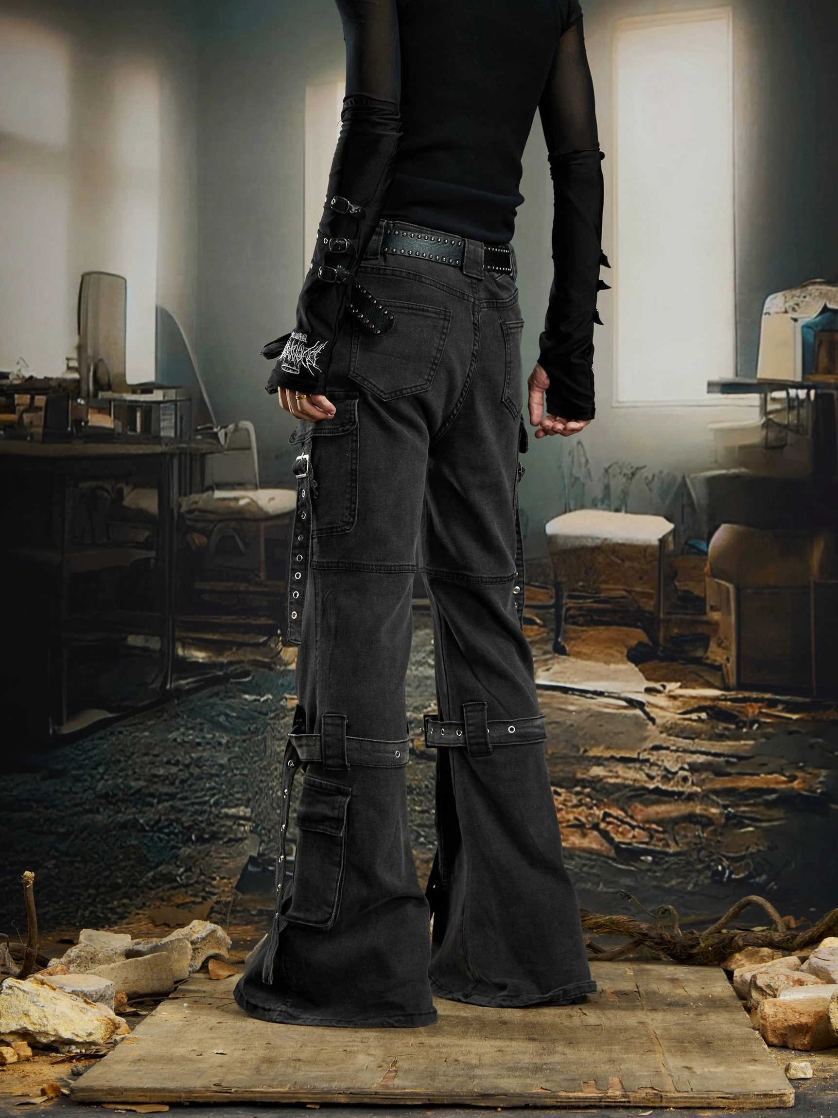 Rear three-quarter view of black gothic cargo flare jeans with back cargo pockets, hardware straps, calf buckles, and dark washed denim