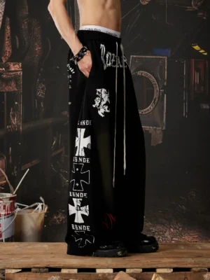 Black gothic graphic wide leg streetwear sweatpants shown from the rear side with cross lettering prints, adjustable drawstring waist, and oversized fit