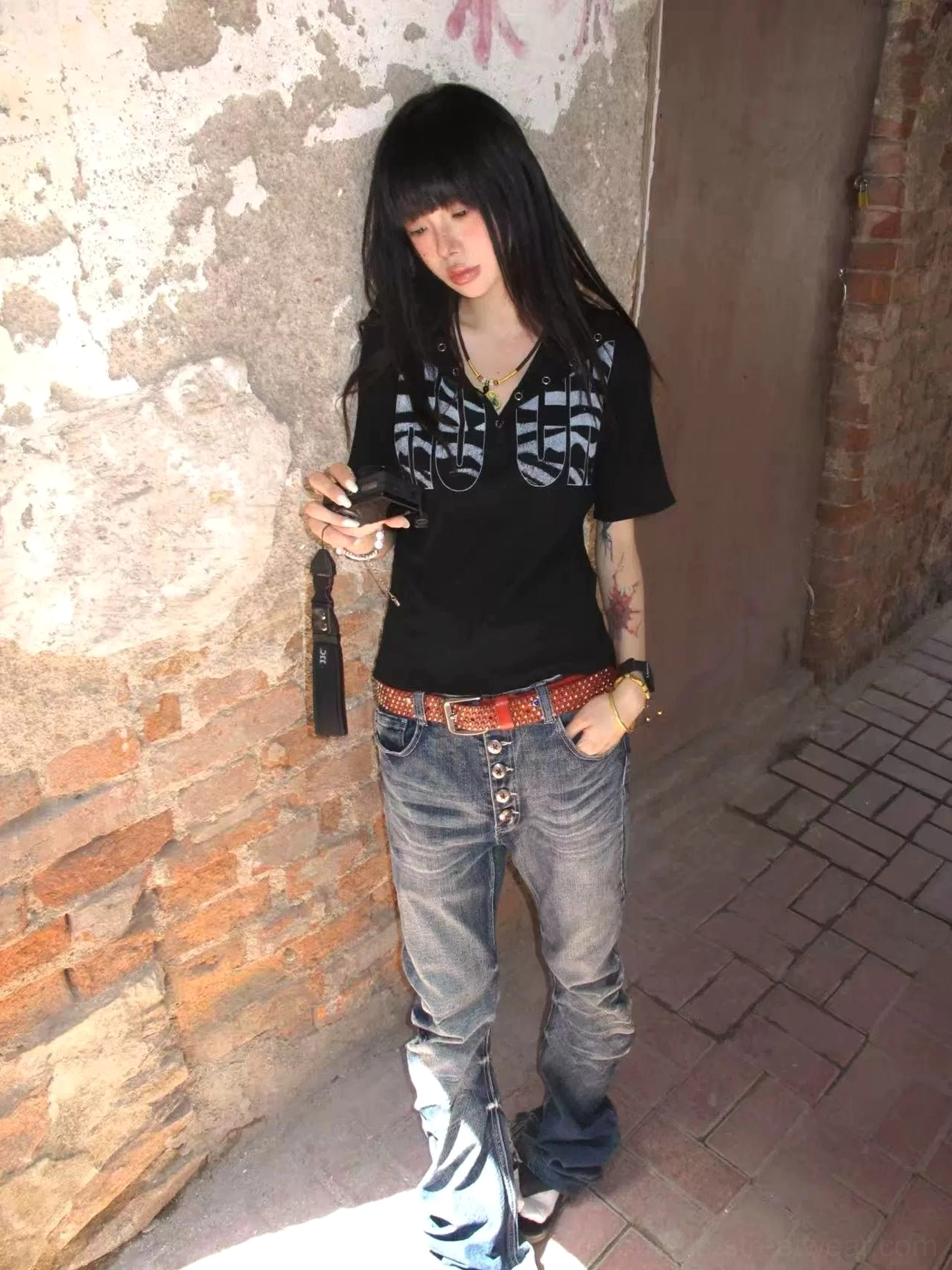 Black gothic hooded graphic tee styled with low-rise flared denim jeans in an alternative streetwear outfit