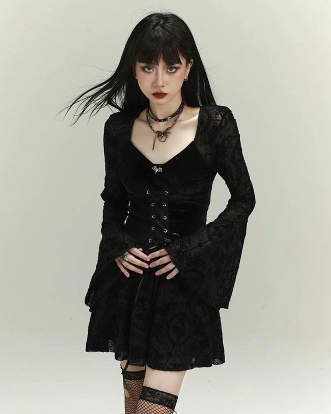 Front view of black gothic lace-up velvet mini dress featuring long flocked lace bell sleeves and layered short skirt