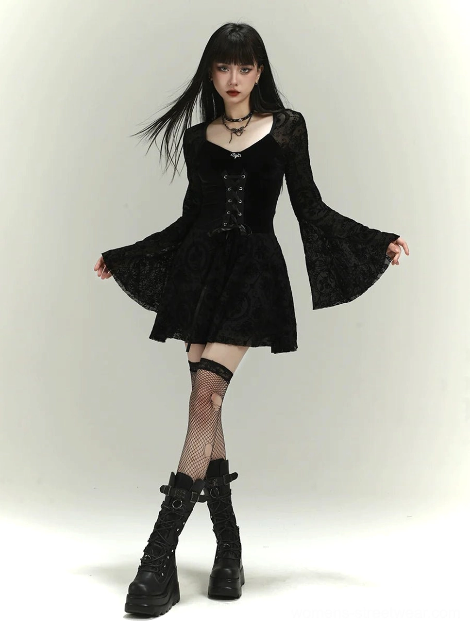 Black gothic lace-up mini dress worn with arms open to show wide floral lace bell sleeves, velvet bodice and A-line skirt