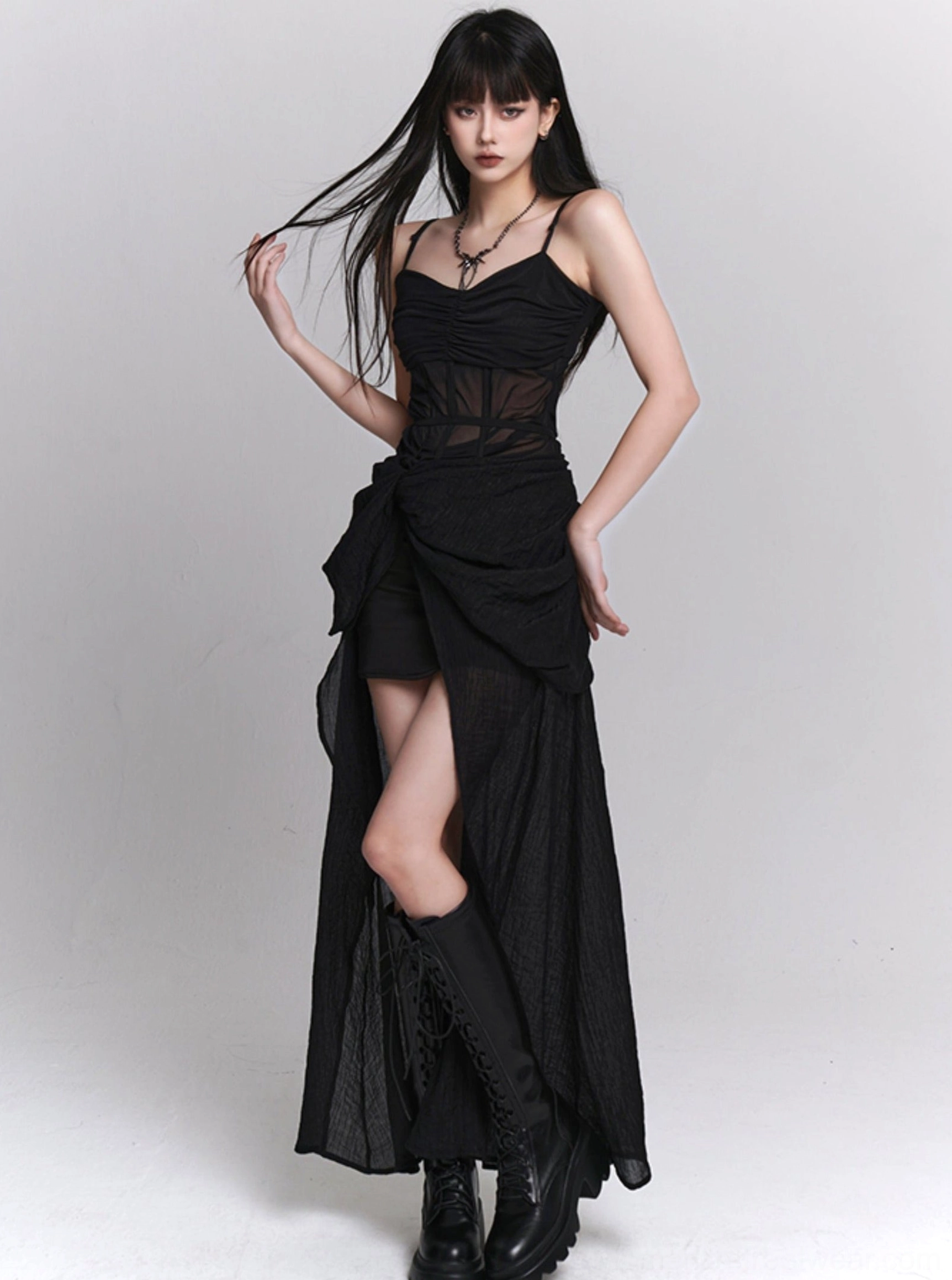 Full-length black gothic slip dress with sheer mesh bodice, twisted draped skirt, asymmetrical hemline, and romantic alternative styling