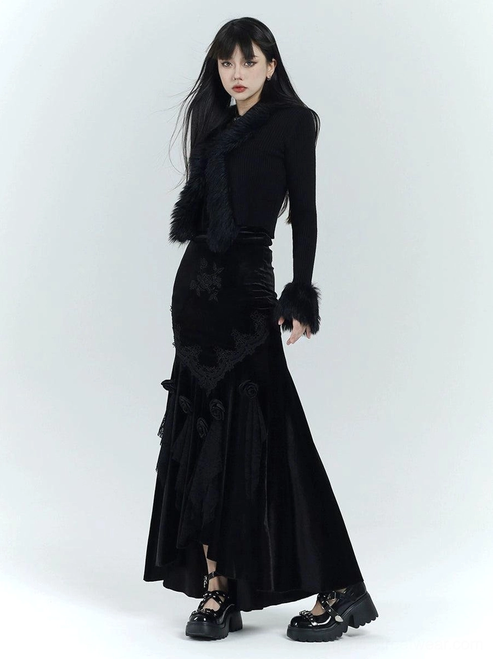 Full body view of a black gothic velvet fishtail dress with floral embroidery, lace appliques, faux fur trim, and platform shoes