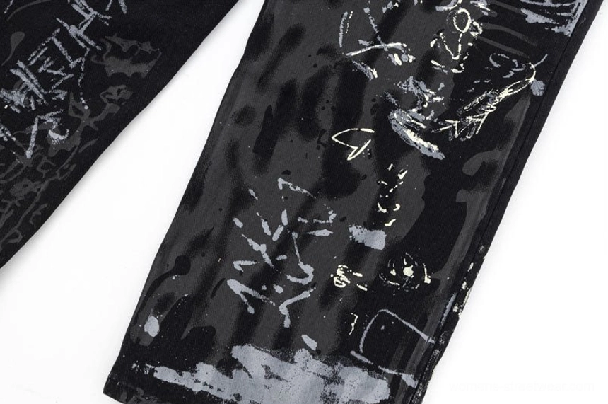 Top-down close-up of black Y2K graffiti print denim jeans featuring layered abstract splatter and sketch details