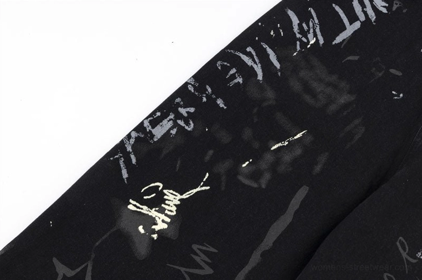 Detailed close-up of signature-style handwritten line art on black graffiti print wide-leg denim jeans