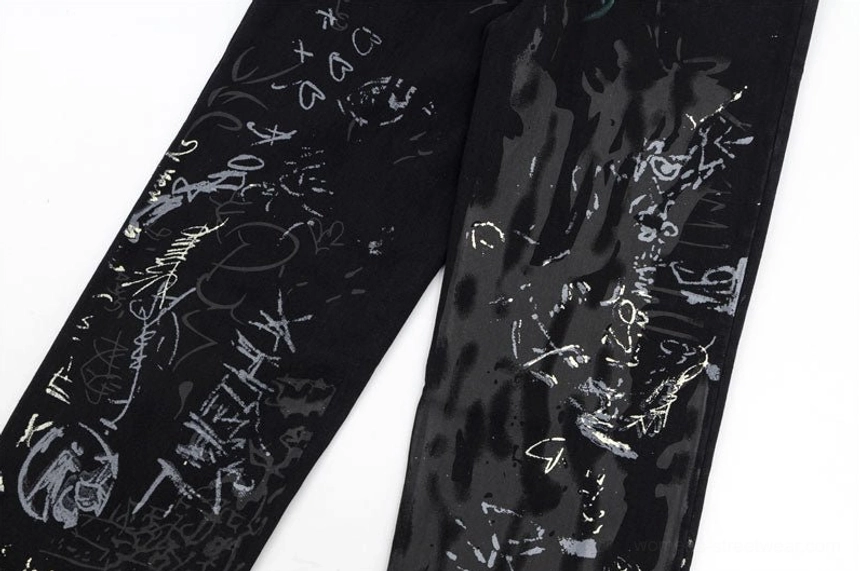 Side leg close-up of black graffiti wide-leg jeans with abstract handwritten street art graphics on denim