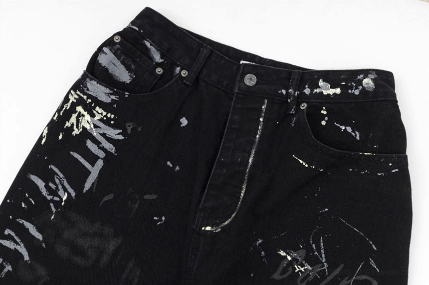 Front waist and pocket close-up of black graffiti print wide-leg jeans with button fly metal rivets and splatter graphics