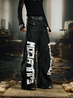 Front view of black graffiti script wide leg denim pants with oversized baggy legs, contrast stitching, and white lettering
