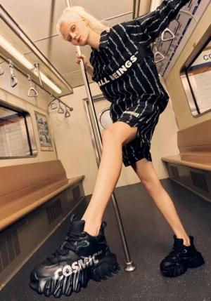 Black chunky platform derby shoes worn in a subway carriage with graphic streetwear styling and sculpted outsole