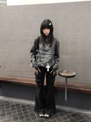 Female model styling a black and gray striped hooded half-zip pullover with flared black cargo pants and cross pendant necklace