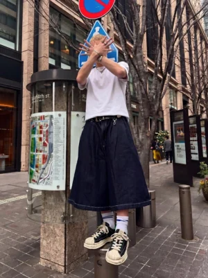 Black and green shell-toe platform sneakers styled with a casual urban streetwear outfit in a downtown city setting
