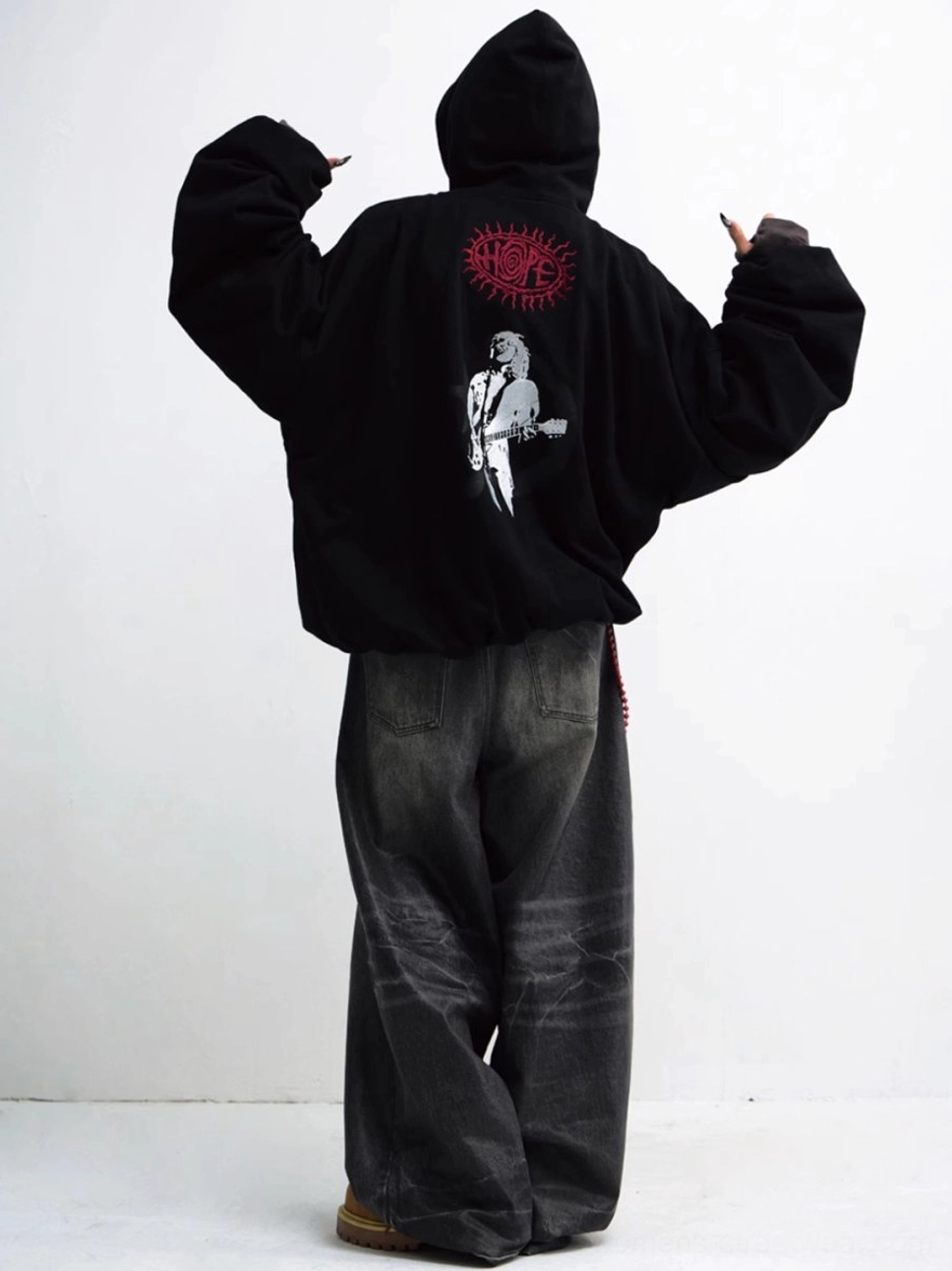 Back view of an oversized black hoodie showing white guitarist artwork and red circular graphic