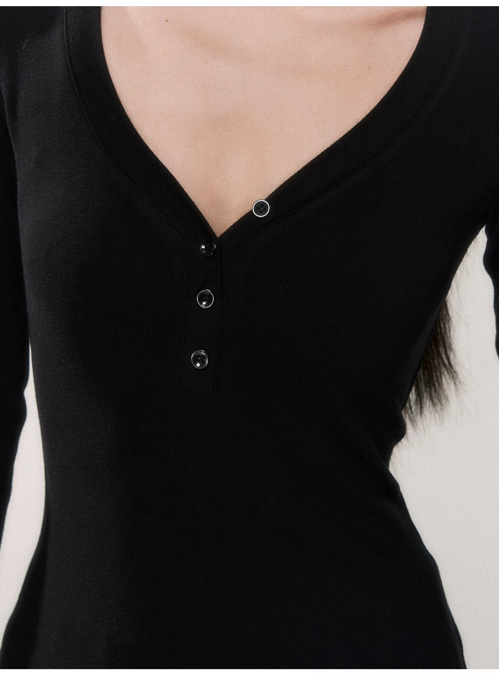 Ultra close-up of four tonal black buttons and the deep V-neckline on a soft fitted henley knit top