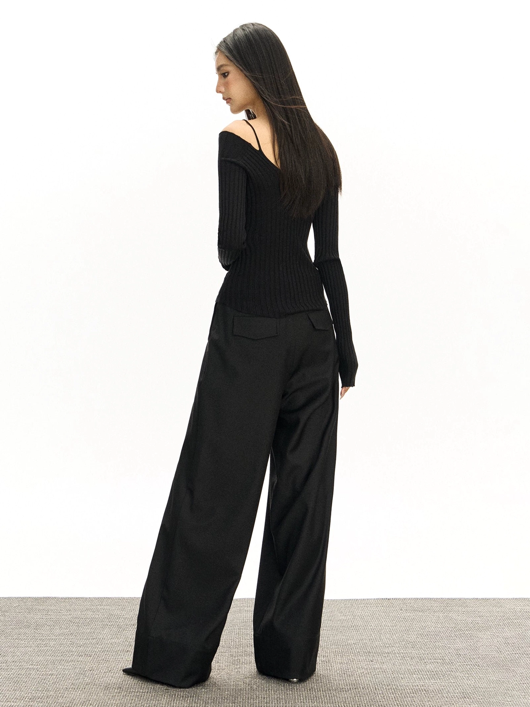 Black high-rise wide-leg tailored trousers shown from the back with two rear waist pockets, neat hemline, and fluid suiting fabric
