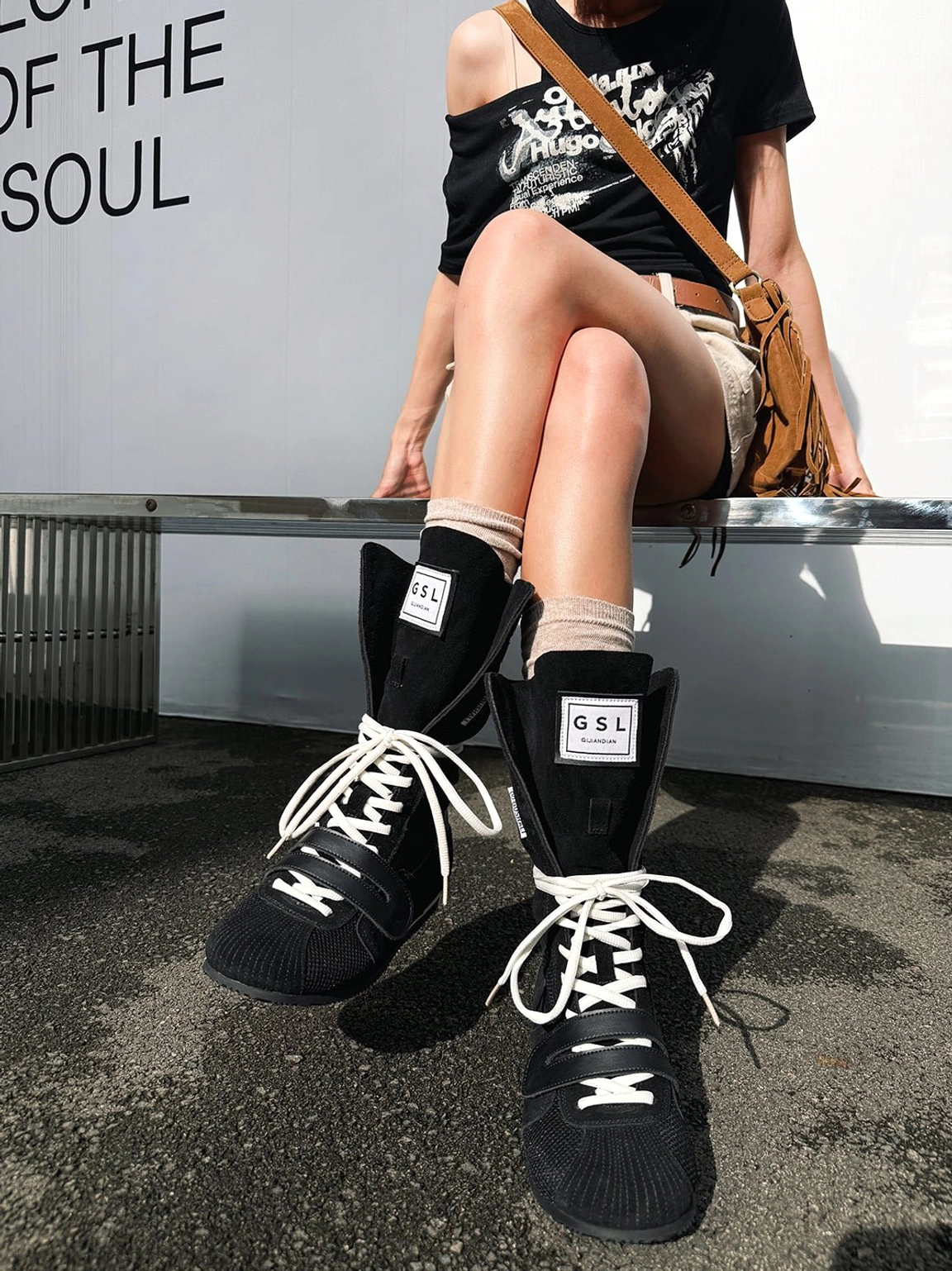 Side view of black high-top boxing trainer boots with contrast white laces styled with light beige socks